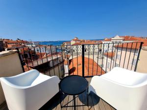 a balcony with two white chairs and a table at Akvatour Apartments Piran in Piran