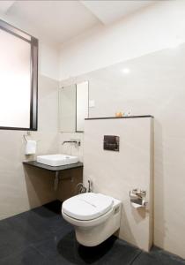 a white bathroom with a toilet and a sink at Hotel The Sudesh in Raipur