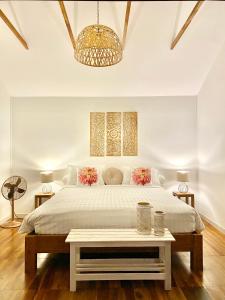 a white bedroom with a large bed and a table at Nibbana Bungalows in Hinkong
