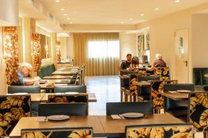 巴塞隆納的住宿－卡利多尼安酒店，一间设有桌子的餐厅,有坐在桌子上的人