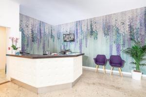 un salón con sillas moradas y un mural de lilas en la pared en Hotel Danieli, en Bibione