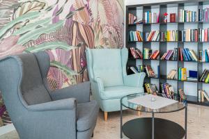 two chairs and a table in front of a book shelf at Hotel Danieli in Bibione