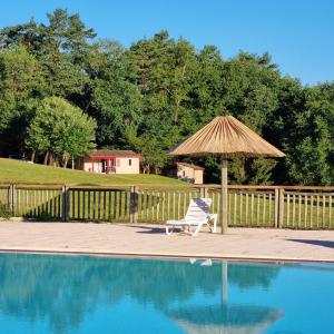 een stoel en een parasol naast een zwembad bij La Forêt Enchantée in Cornille