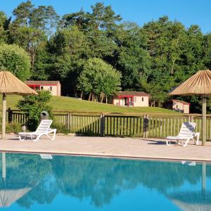 2 sillas y sombrillas junto a una piscina en La Forêt Enchantée, en Cornille