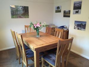 a dining room table with a vase of flowers on it at Llys y Coed in Brechfa