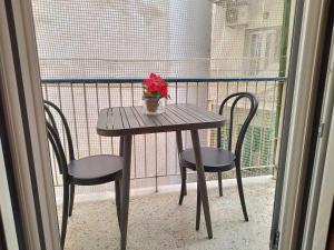 una mesa con 2 sillas y un jarrón de flores en el balcón en Zeus Apartment en Athens