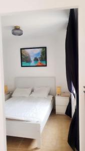 a bedroom with a white bed with a picture on the wall at Bandaithai in Zandvoort