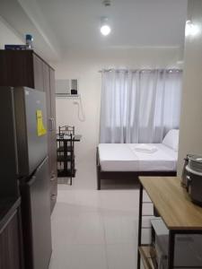 a small kitchen with a bed and a refrigerator at Cozy235 studio at The Persimmon in Cebu City
