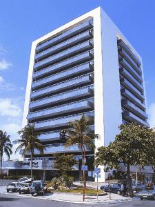 un gran edificio blanco con coches estacionados frente a él en Littoral Tambaú Flat, en João Pessoa