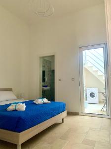 a bedroom with a blue bed and a sliding glass door at Le Margherite Holiday Home - Campomarino di Maruggio, zona Acquadolce Cirenaica in Maruggio