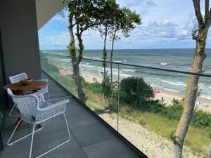 a balcony with a table and chairs and the ocean at APARTAMENT 36 na klifie z widokiem na morze ADULTS ONLY in Rewal