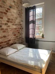 łóżko w pokoju z ceglaną ścianą w obiekcie Hostel BAZA 15 we Wrocławiu
