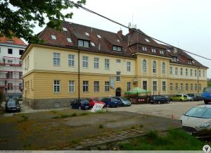 a large yellow building with cars parked in front of it at Hostel BAZA 15 in Wrocław