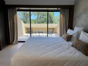 a bedroom with a large white bed and a balcony at Hôtel Spa & Restaurant - Son de Mar in Porto-Vecchio