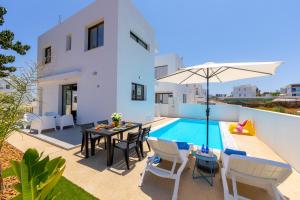 a villa with a pool and a table and chairs at Alasia Villas in Paralimni