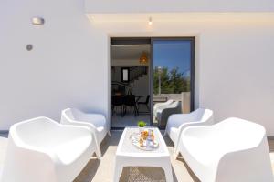 a patio with white chairs and a table with a cake on it at Alasia Villas in Paralimni