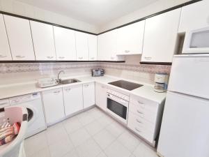 eine weiße Küche mit einer Spüle und einem Kühlschrank in der Unterkunft Dunas y Luz in Rota