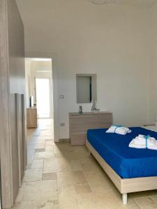 una camera con letto blu e specchio di Le Margherite Holiday Home - Campomarino di Maruggio, zona Acquadolce Cirenaica a Maruggio
