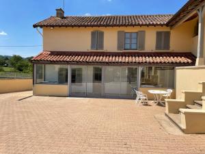 a house with a patio and a table in front of it at Gîte les 3 eucalyptus in Cluny