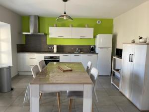 a kitchen with a table and white cabinets and green walls at Gîte les 3 eucalyptus in Cluny