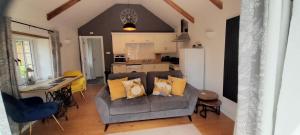 a living room with a couch and a table and a kitchen at Stunning cosy barn in peaceful rural Cornwall in Truro