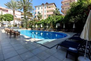 a swimming pool with tables and chairs next to a building at May Flower Apart Hotel in Alanya