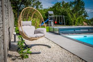 - une chaise en osier près de la piscine dans l'établissement Villa Uno Balaton, à Balatonakarattya