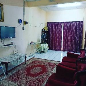 a living room with a red couch and a tv at Homestay Musafir 3.0 in Seri Iskandar +1 photo