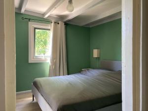 een groene slaapkamer met een bed en een raam bij De Weide Blick in Biggekerke