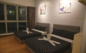 duas camas com pessoas deitadas sobre elas num quarto em Regalia Residence KLCC View by iLuxHome em Kuala Lumpur