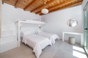 two beds in a bedroom with white walls and wooden ceilings at Etesian Villas in Batsi +26 photos