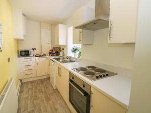 a kitchen with white cabinets and a stove top oven at Tulip Cottage in Shipley