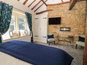 a bedroom with a blue bed and a stone wall at Tulip Cottage in Shipley