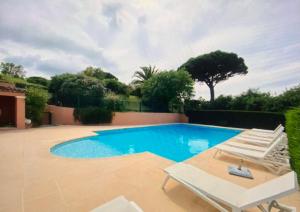 a swimming pool with two lounge chairs and a swimming pool at Villa vue mer donnant sur le Golfe de St Tropez, 2 chambres, 6 pers, piscine commune in Saint-Tropez