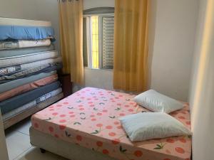 Un pequeño dormitorio con una cama con flores. en Casa de praia aconchegante próxima ao centro, en Mongaguá
