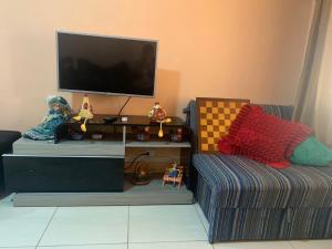 a living room with a couch and a flat screen tv at Casa de praia aconchegante próxima ao centro in Mongaguá