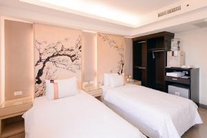 two white beds in a room with a wall at Kiwi Express Hotel - Kaohsiung Station in Kaohsiung