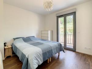 a bedroom with a bed and a large window at Superbe appartement entièrement rénové au pied des montagnes avec parking inclus in Bagnères-de-Bigorre