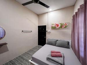 een slaapkamer met een bed en een plafondventilator bij BELLA COTTAGE in Pantai Cenang