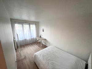 een witte slaapkamer met een bed en een bureau bij Ambiance, convivialité et emplacement in Orléans