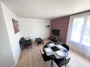 uma sala de estar com uma mesa e cadeiras e uma parede de tijolos em Ambiance, convivialité et emplacement em Orléans