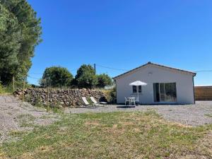 une petite maison blanche avec un mur en pierre dans l'établissement Gîte Les Mimosas - 2 à 4 personnes - Vue imprenable, à Largentière
