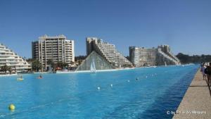 una gran piscina de agua con edificios en el fondo en San Alfonso Apartment, en Algarrobo