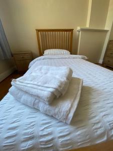 a white bed with towels on top of it at Cheerful 3 Bedroom house just across tube station in London
