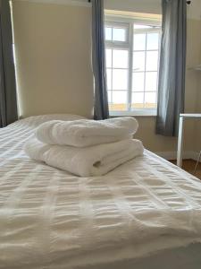 a pile of towels sitting on top of a bed at Cheerful 3 Bedroom house just across tube station in London