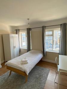 a bedroom with a bed and two windows at Cheerful 3 Bedroom house just across tube station in London