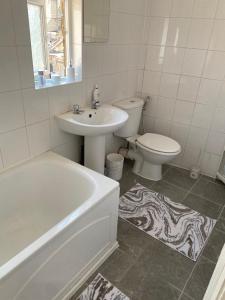 a bathroom with a sink and a tub and a toilet at Cheerful 3 Bedroom house just across tube station in London