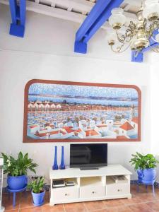 una sala de estar con TV y una pintura en la pared en “Flor de Sal” Charming Traditional Andalusian House, en Ayamonte