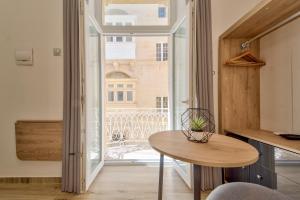 Zimmer mit einem Tisch und Blick auf ein Gebäude in der Unterkunft Tritoni Mini Studios - Valletta in Floriana