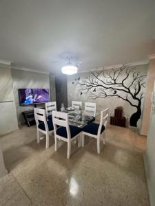 a dining room with a table with chairs and a tree mural at madrigal 1-3br with parking in Santiago de los Caballeros